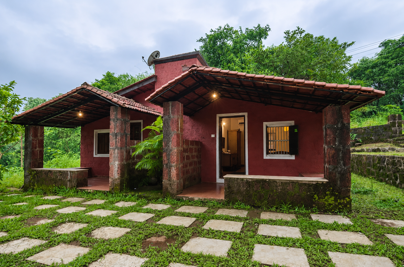 Red heritage cottage with tiled roof in lush greenery
